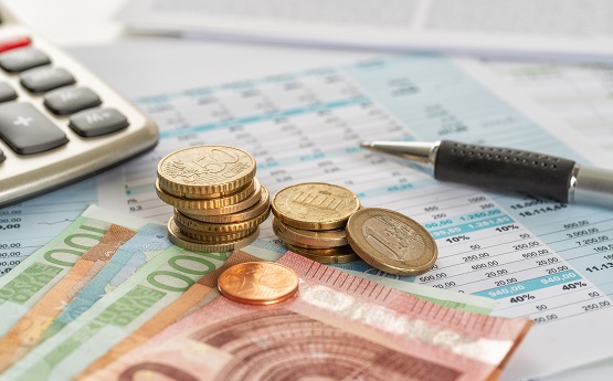 Symbolbild: Scheine und Münzen mit Dokumenten