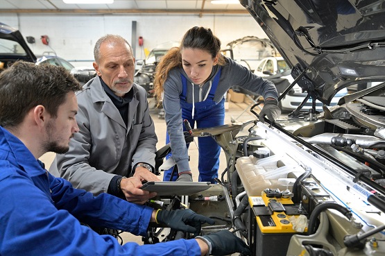 Instructor with trainees working on car engine Symbolbild: Azubis und Chef