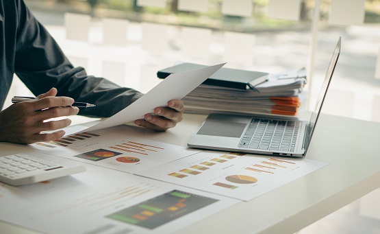 Business analytics team examining financial statements to verify internal control system, accounting firm, accountant working on laptop while checking home invoice or financial documents. Symbolbild: Business Analytics, Laptop